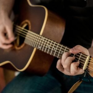 A musician strums chords on an acoustic guitar, showcasing musical talent.
