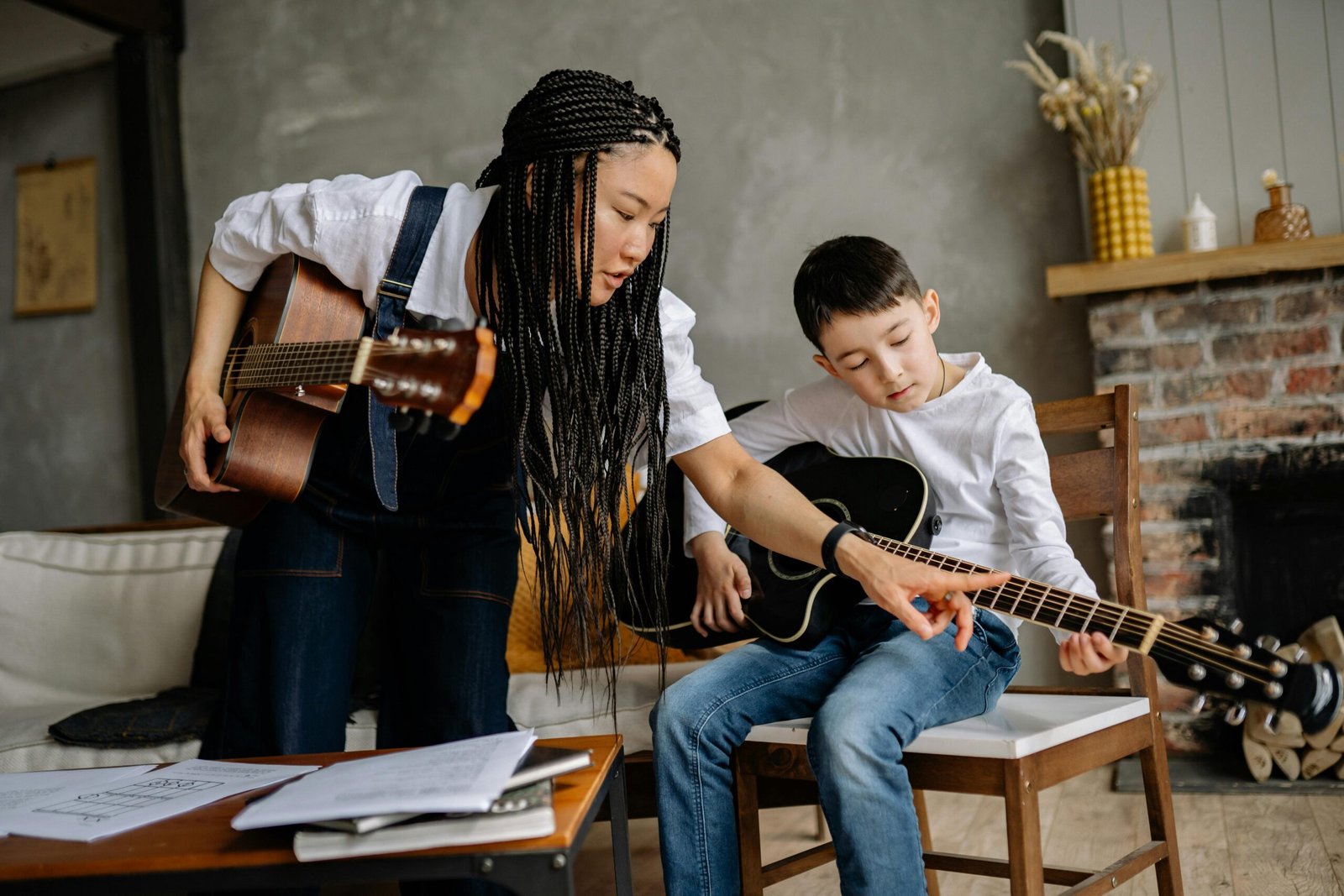 Instructor teaching child to play acoustic guitar in a warm, inviting living room setting.